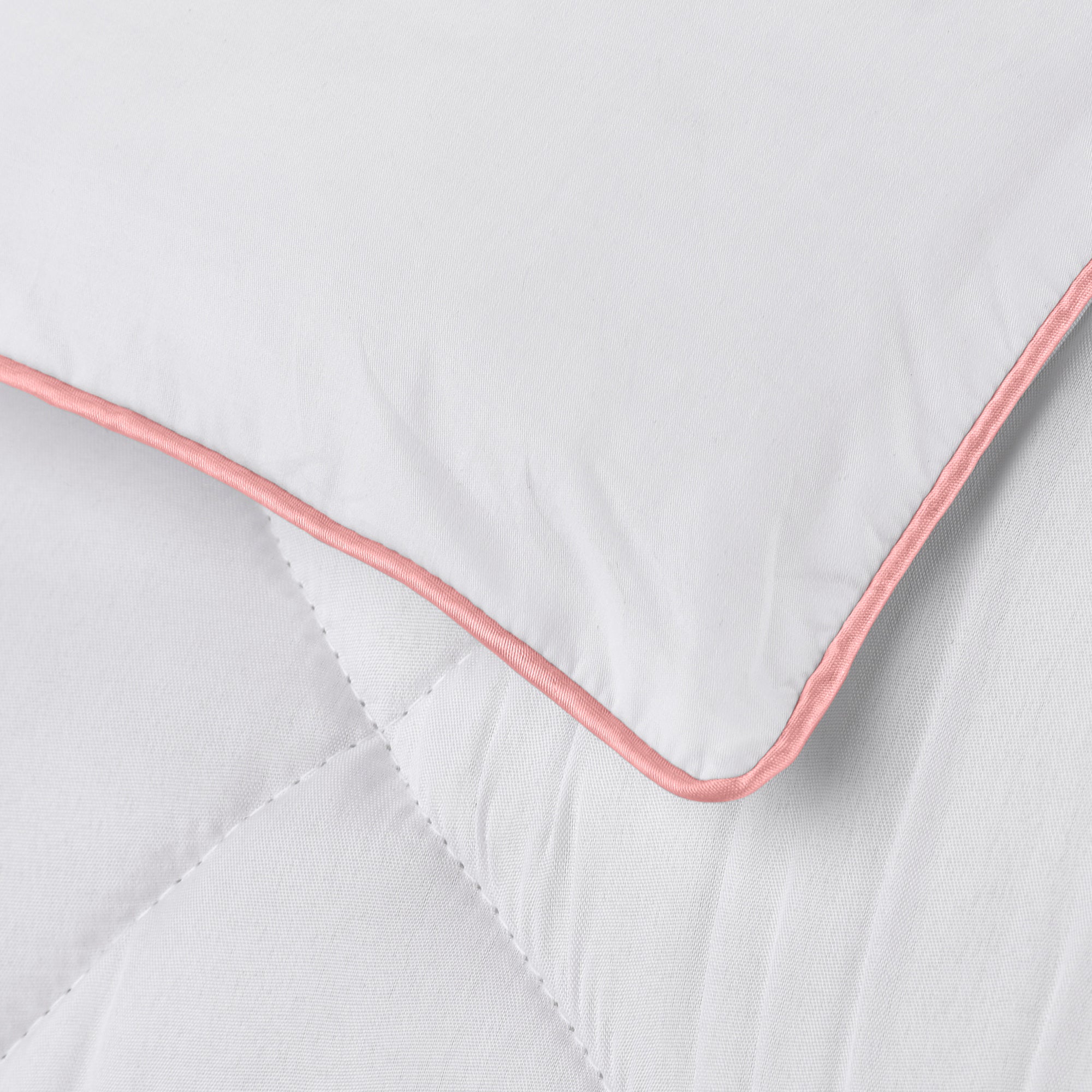 Detail of the Pillow Gal Down Alternative Mattress Pad showing white elastic side skirt and pink satin welt cord on the top edge