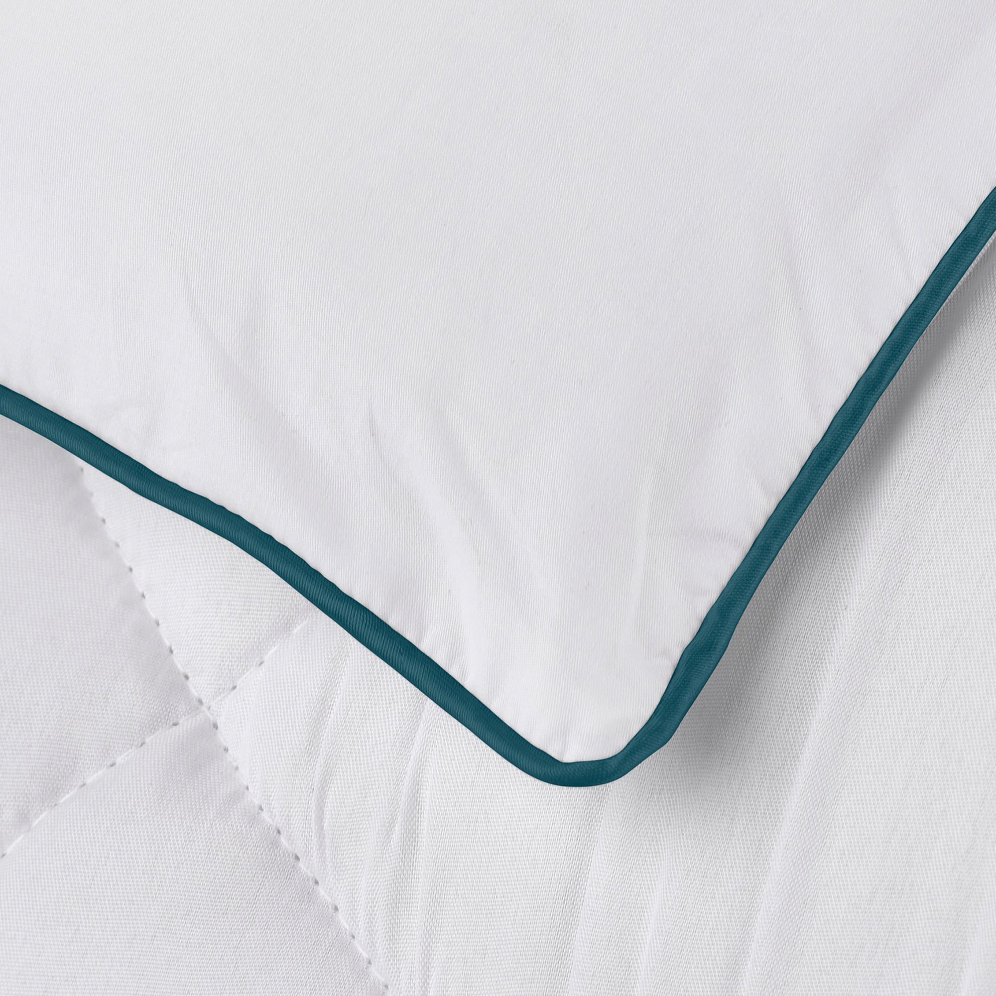 Detail of the Pillow Guy Down Alternative Mattress Pad showing white elastic side skirt and blue satin welt cord on the top edge